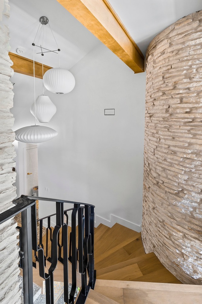 stairwell with pendant lighting and textured stone wall in Austin TX by RedOven Builds