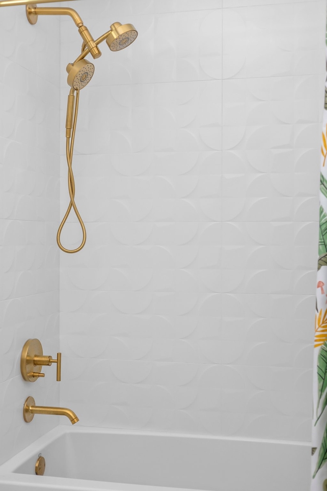 walk in shower with white tile and gold fixtures by RedOven Builds Austin TX remodel