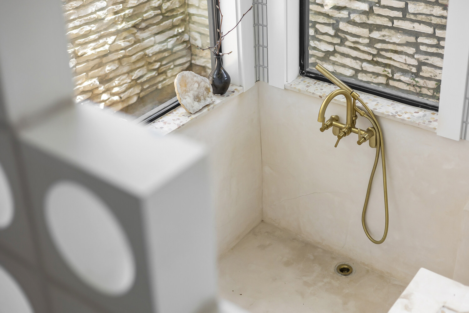 walk-in shower with brass fixtures and stone walls in full home remodel by RedOven Builds in Austin TX