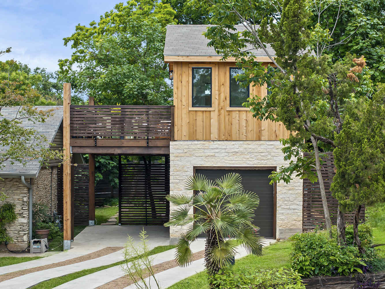 Close-up exterior of wood-clad ADU with balcony and garage by RedOven Builds in Austin, TX