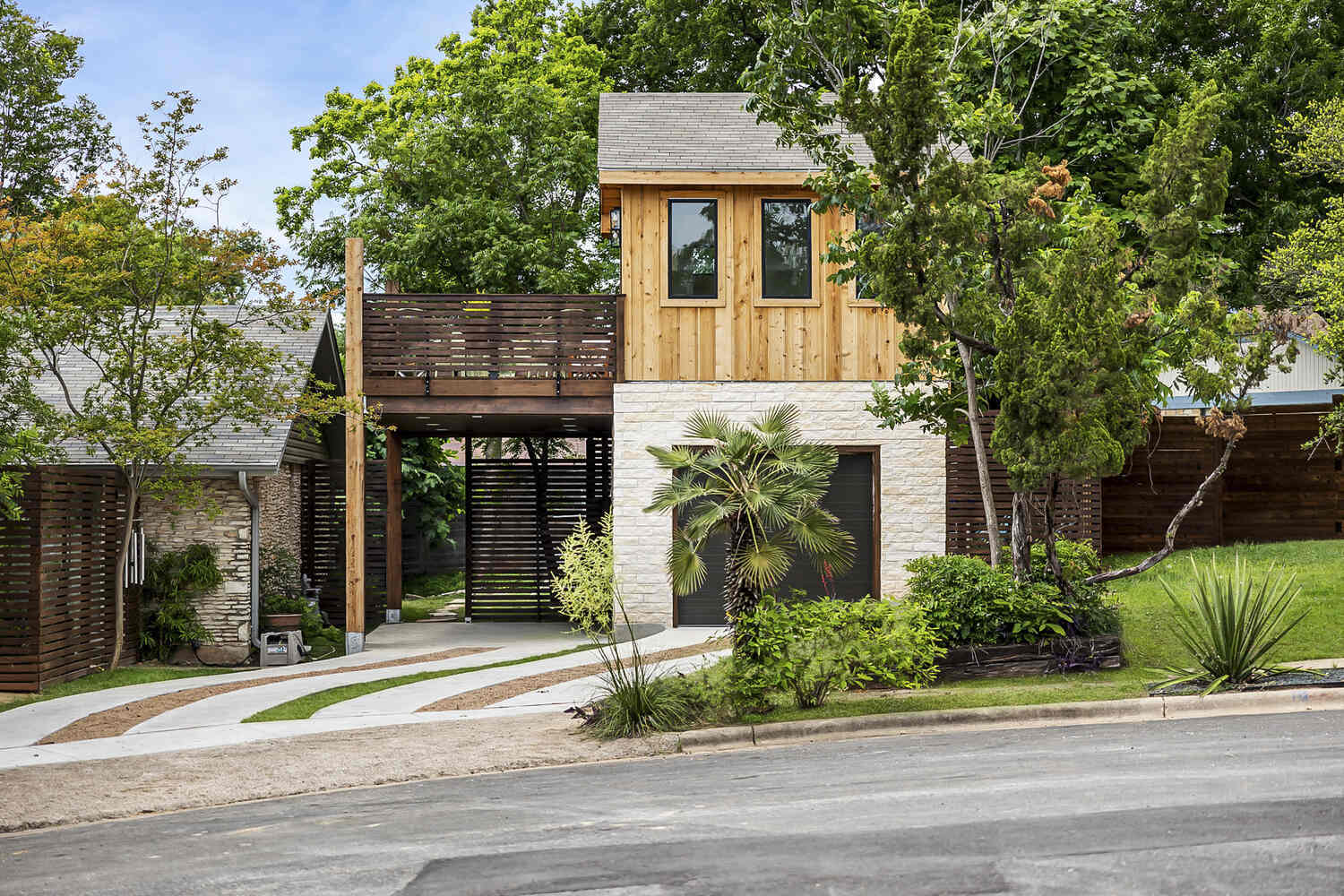 Exterior view of modern ADU with wood siding, elevated deck, and landscaped yard by RedOven Builds in Austin, TX