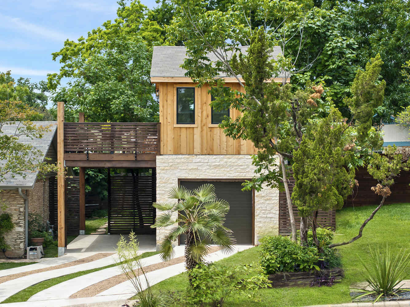 Front exterior of custom ADU with wood siding and lush landscaping by RedOven Builds in Austin, TX
