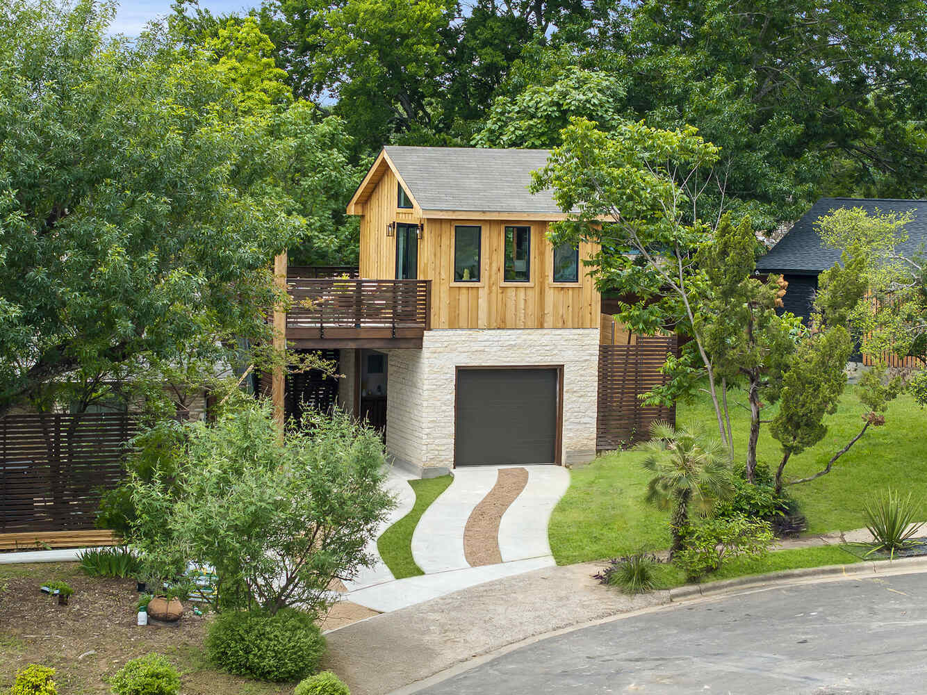 Modern backyard ADU with natural wood siding and garage by RedOven Builds in Austin, TX