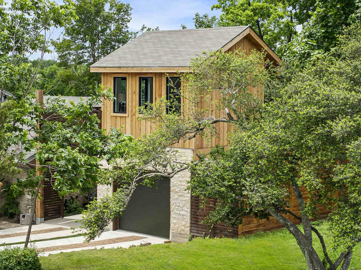 Rear angle of custom ADU with wood siding and surrounding trees by RedOven Builds in Austin, TX