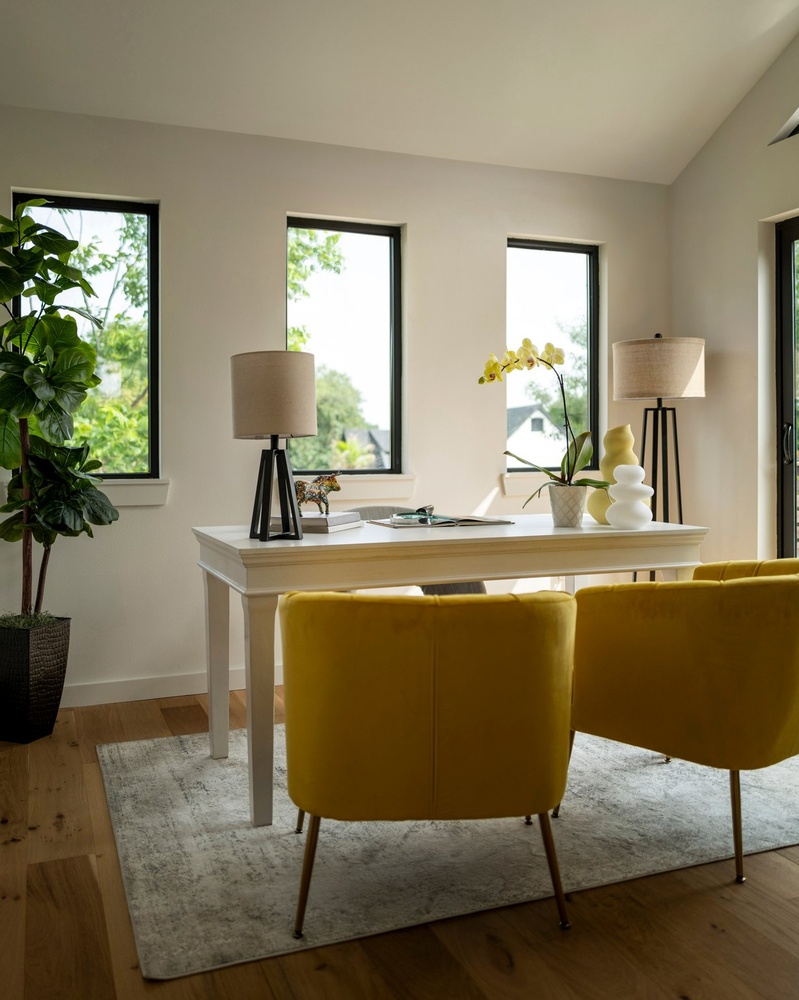 RedOven Builds ADU interior office with yellow chairs, white desk, and large windows in Austin, TX