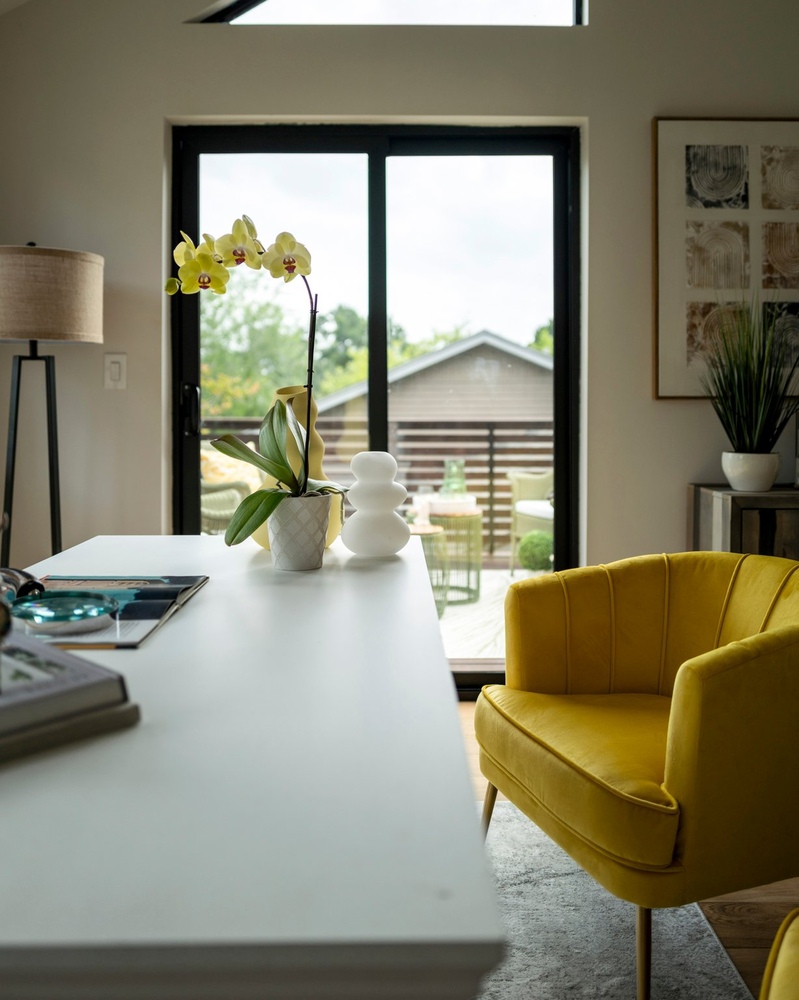 RedOven Builds ADU interior with desk, yellow chair, and sliding doors to deck in Austin, TX