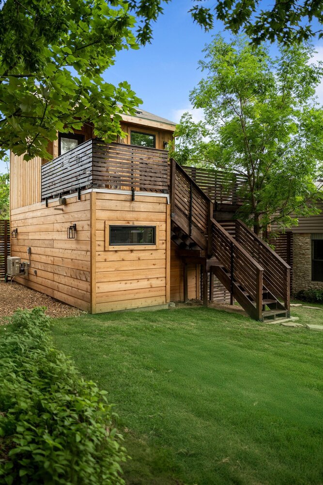 RedOven Builds ADU side view with exterior staircase, wood siding, and balcony in Austin, TX
