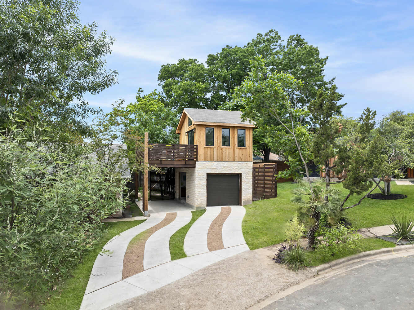 Wide shot of ADU with curved driveway and surrounding trees by RedOven Builds in Austin, TX