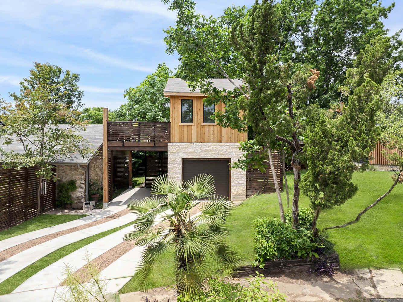 Wide view of custom ADU with curved driveway and mature landscaping by RedOven Builds in Austin, TX
