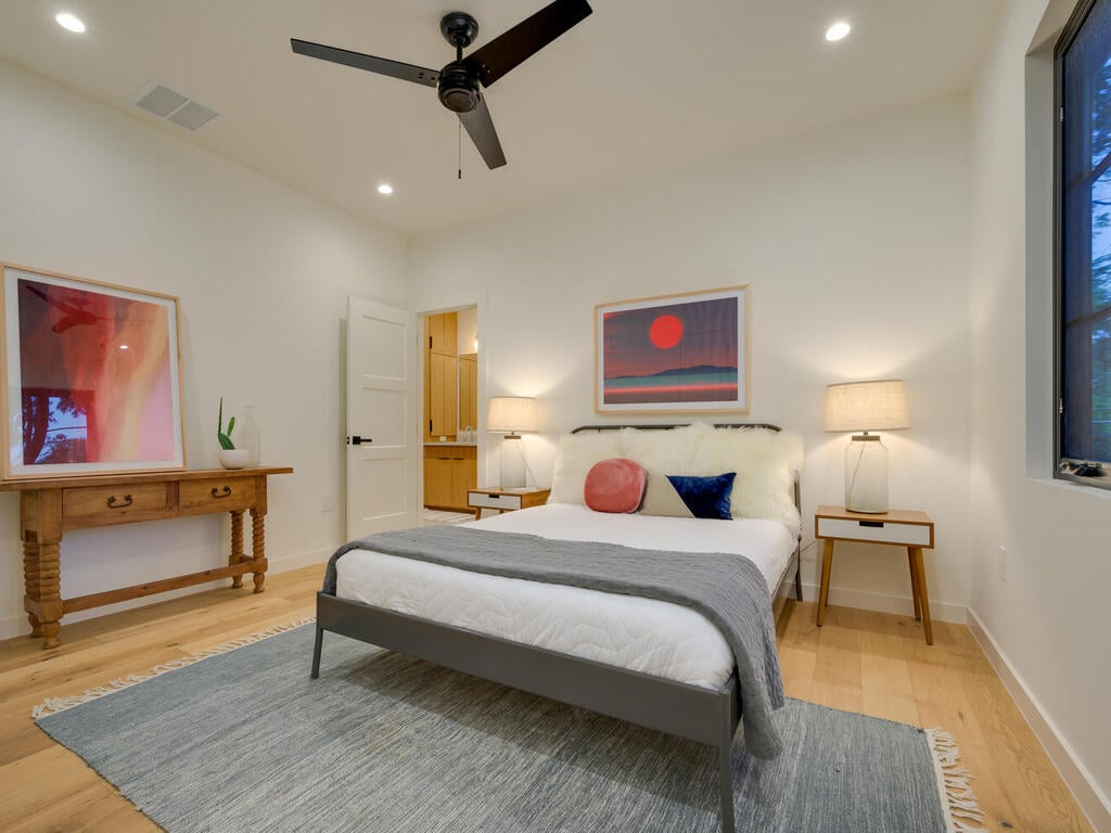 Contemporary bedroom with ceiling fan and neutral palette by RedOven Builds in Austin, TX