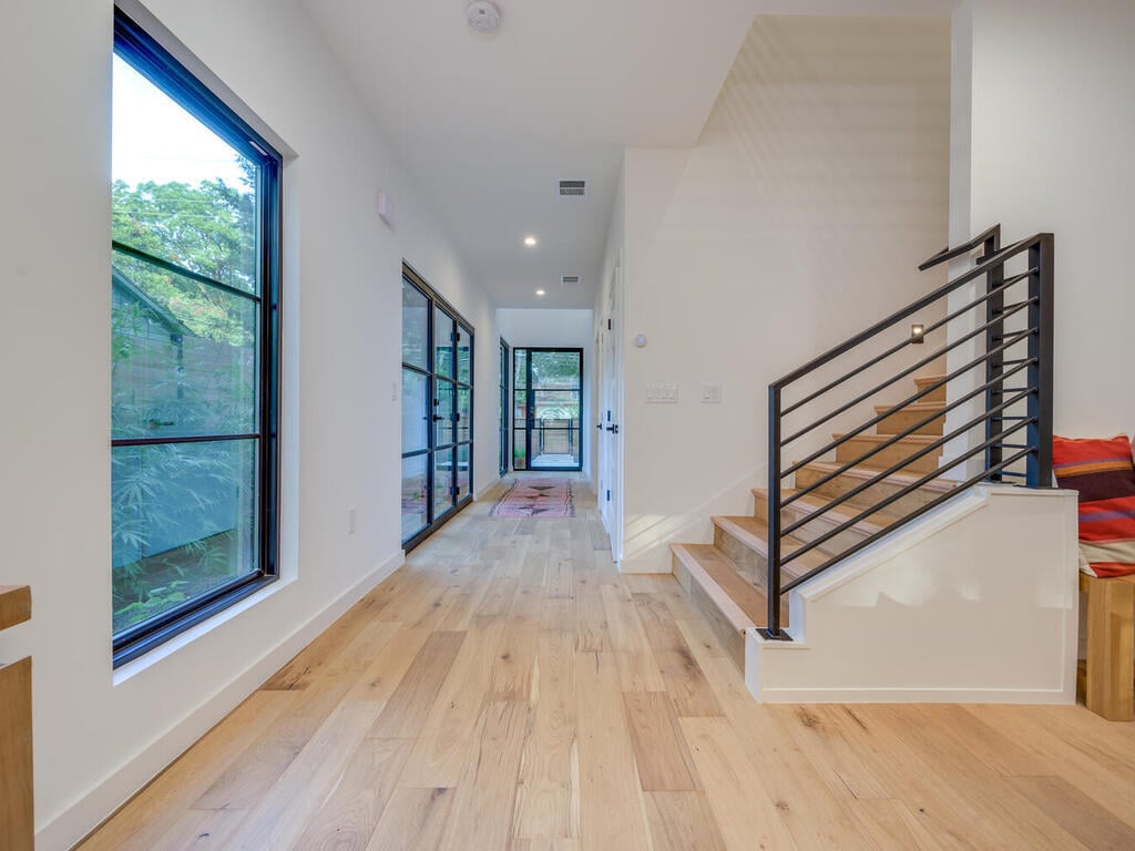 Modern interior corridor with stair railing and natural light by RedOven Builds in Austin, TX