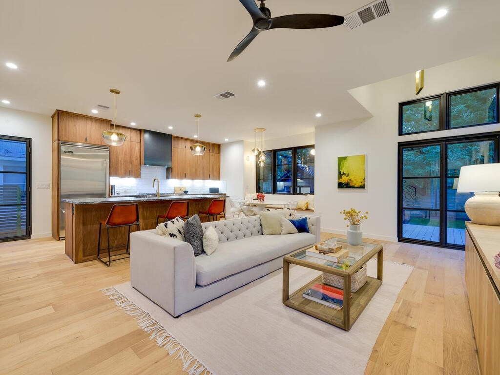 Modern living space with kitchen island and natural light by RedOven Builds in Austin, TX