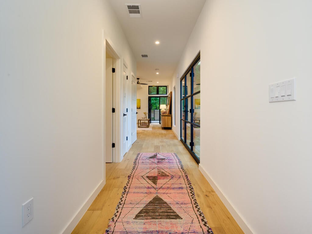 Modern new build hallway with clean lines and hardwood floors by RedOven Builds in Austin, TX