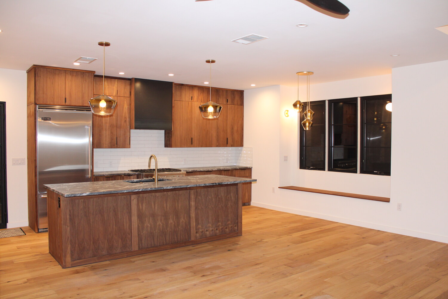 RedOven Builds modern kitchen with wood cabinetry, large island, and pendant lighting in Austin, TX