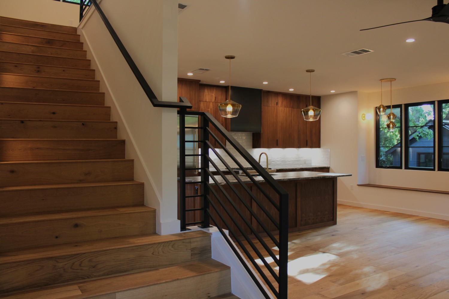 RedOven Builds staircase with wood steps and black metal railing in modern Austin, TX home