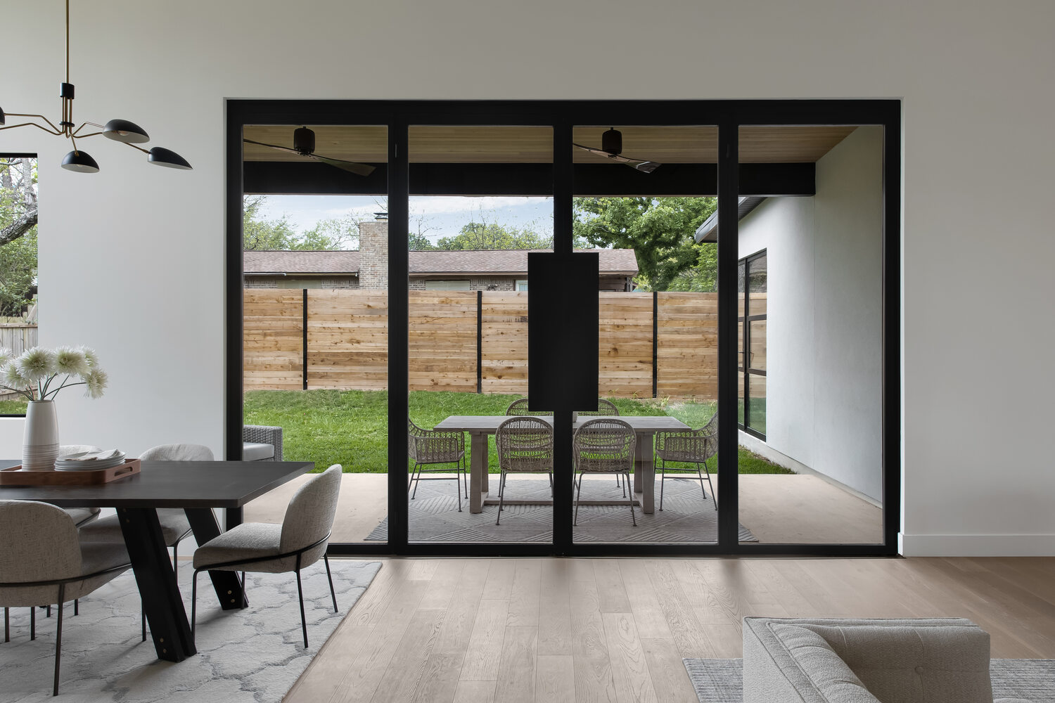 Custom home dining space with expansive glass doors and outdoor seating by RedOven Builds in Austin, TX
