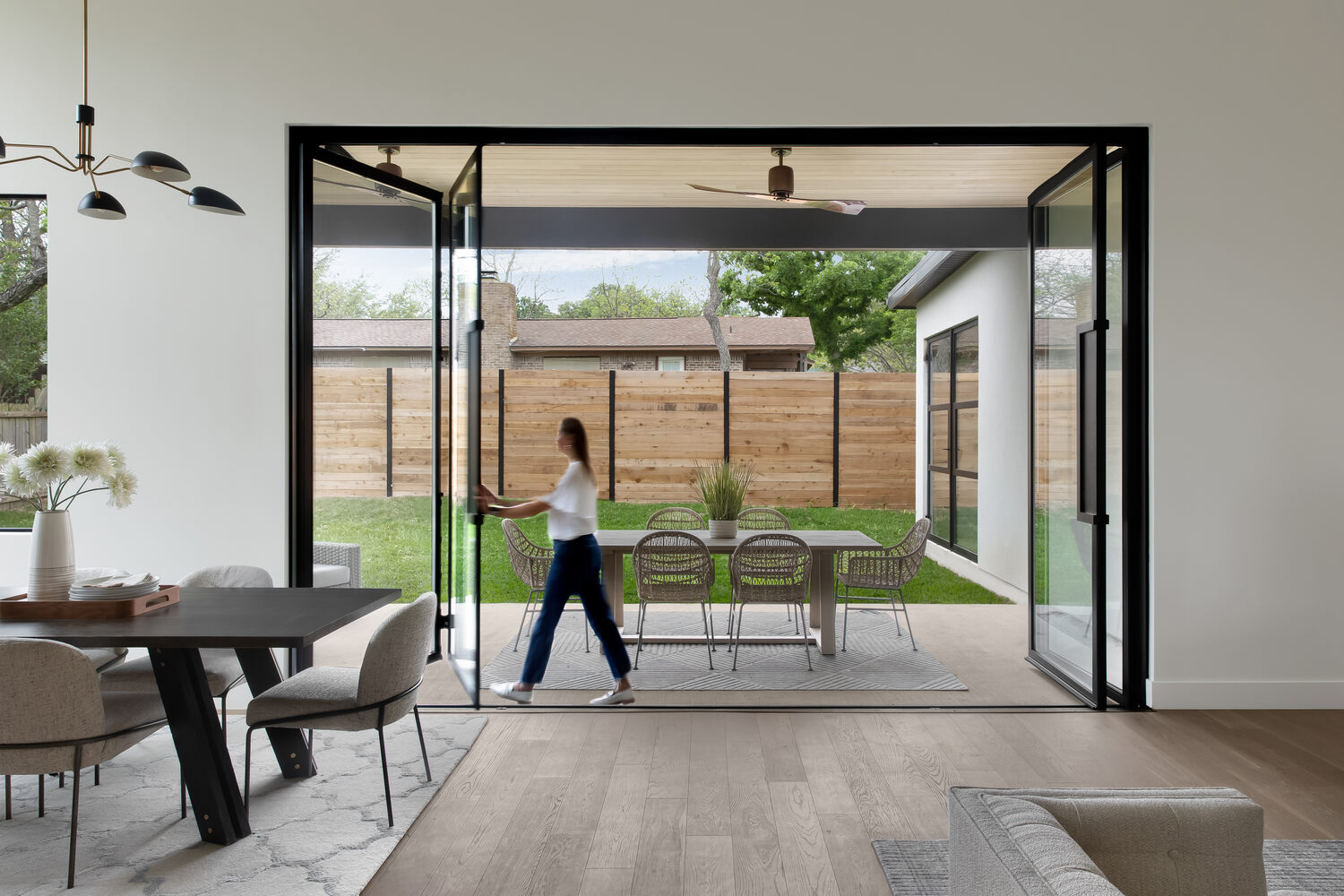 Modern home with large folding glass doors opening to patio by RedOven Builds in Austin, TX