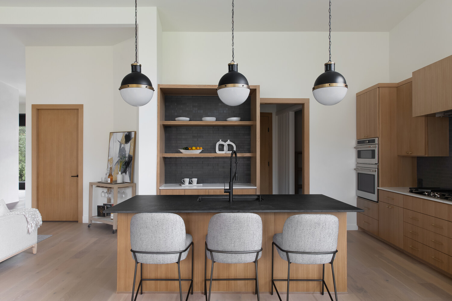 RedOven Builds modern kitchen with large island, wood cabinetry, and pendant lighting in Austin, TX