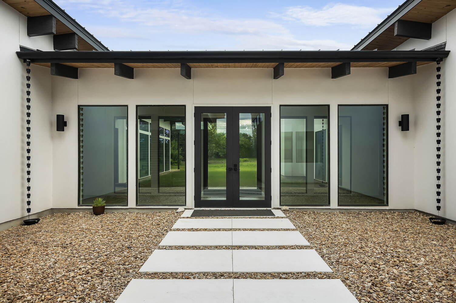Contemporary backyard entrance with large windows and stepping stones in RedOven Builds new build Rio Grande, TX