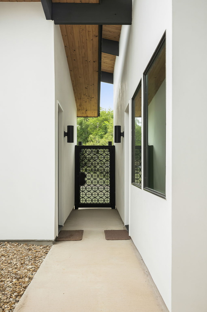Exterior walkway with modern overhang and wood ceiling in RedOven Builds custom home Rio Grande, TX