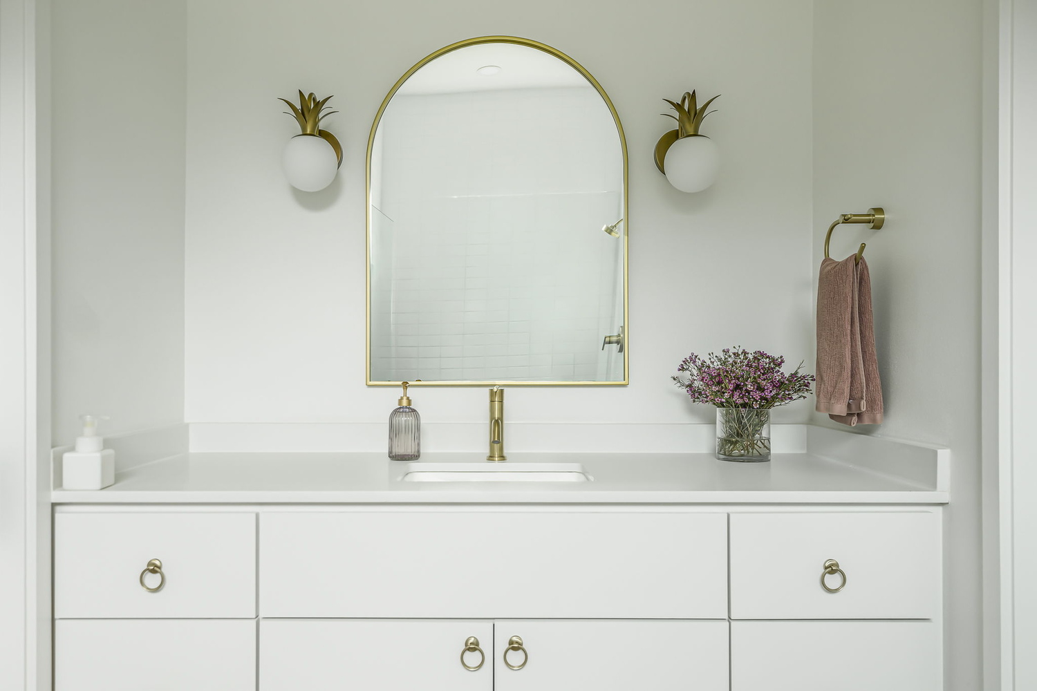 RedOven Builds bathroom with white vanity, gold fixtures, and arched mirror in Rio Grande TX