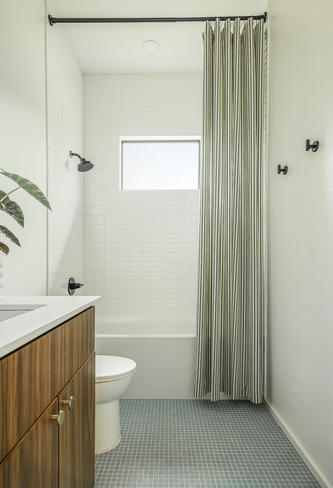 clean and modern bathroom layout in RedOven Builds home with white tile and natural wood accents in Rio Grande TX