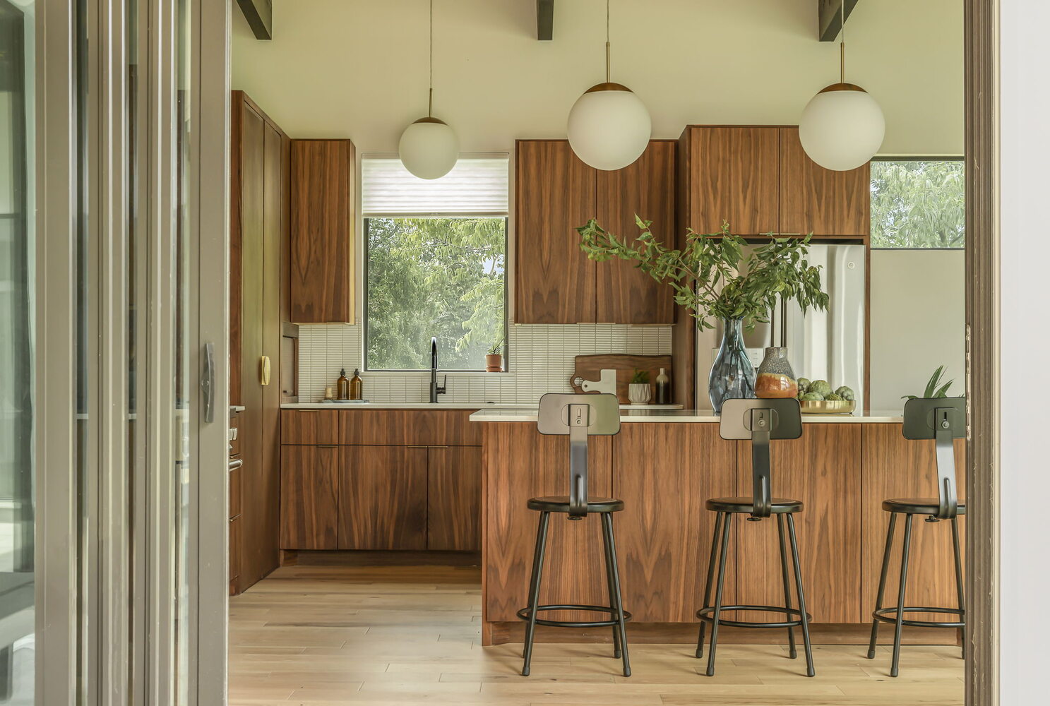 contemporary kitchen with wood cabinetry and white island in RedOven Builds custom new build San Juan Dr Rio Grande TX