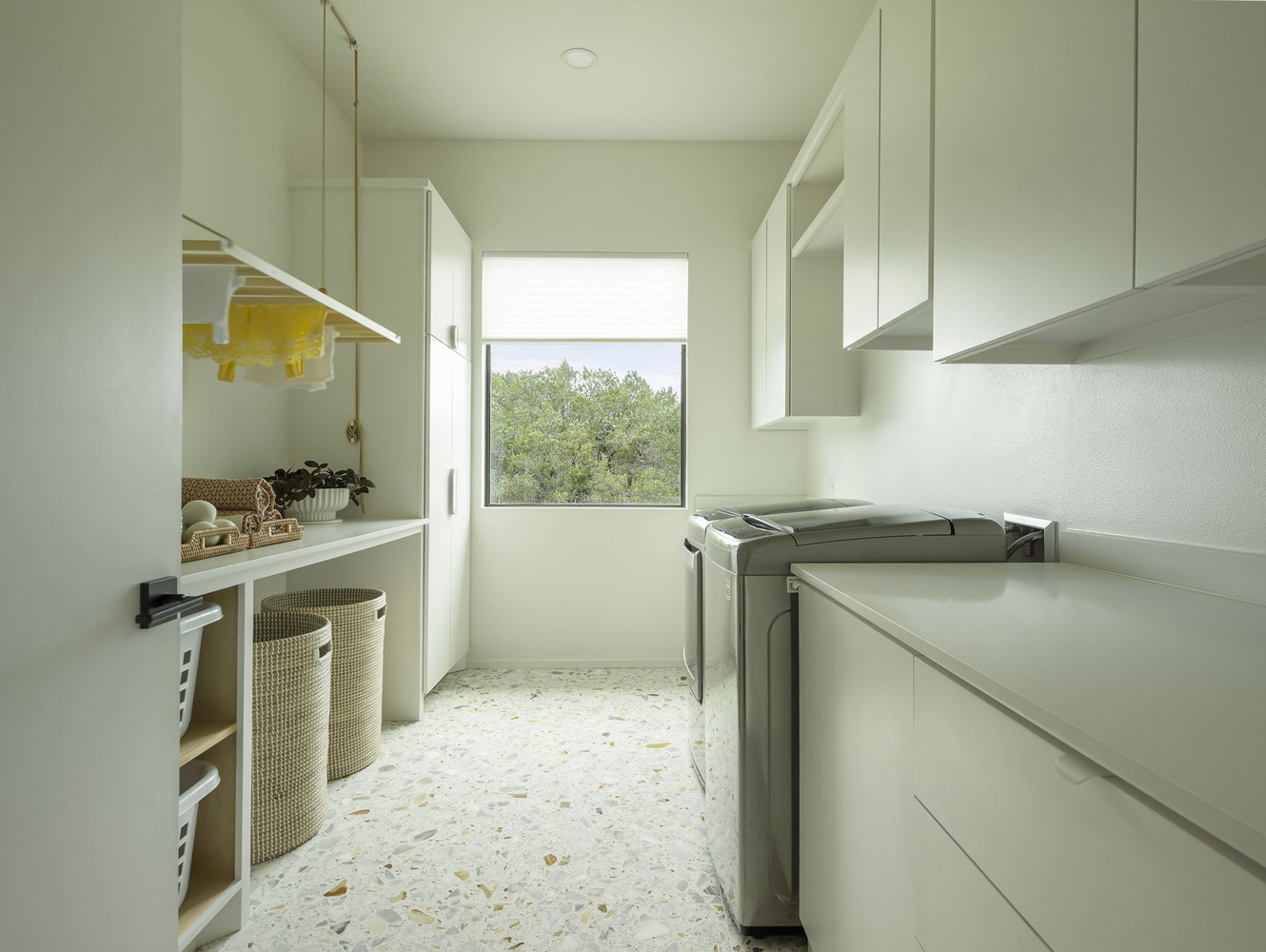 custom home laundry room with natural light, white cabinets, and folding space by RedOven Builds in Rio Grande TX