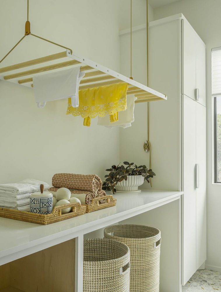 custom laundry space with hanging clothes rack and woven baskets by RedOven Builds in Rio Grande TX