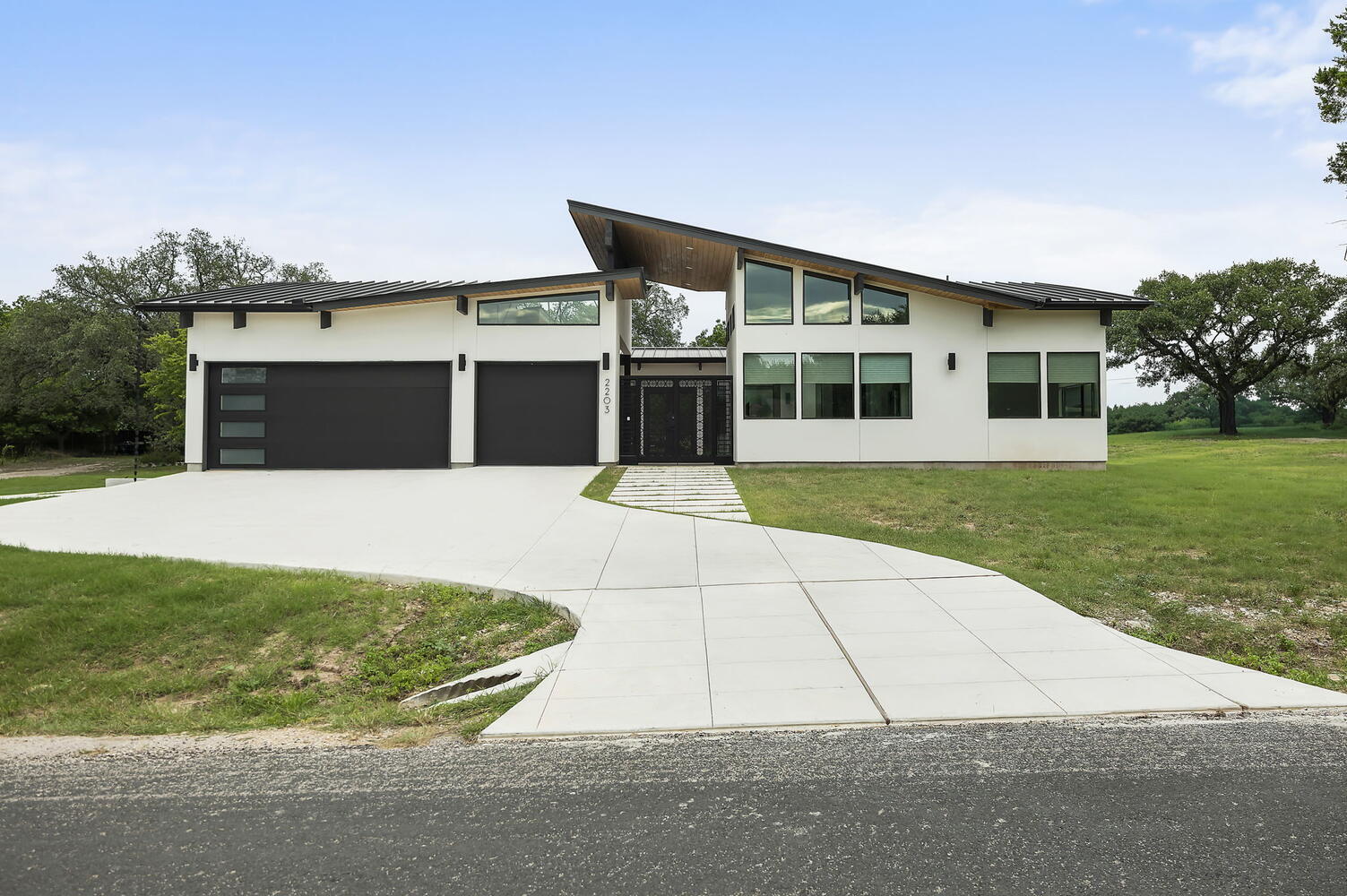 front elevation of modern custom home with sloped roof and driveway by RedOven Builds in San Juan Dr Rio Grande TX