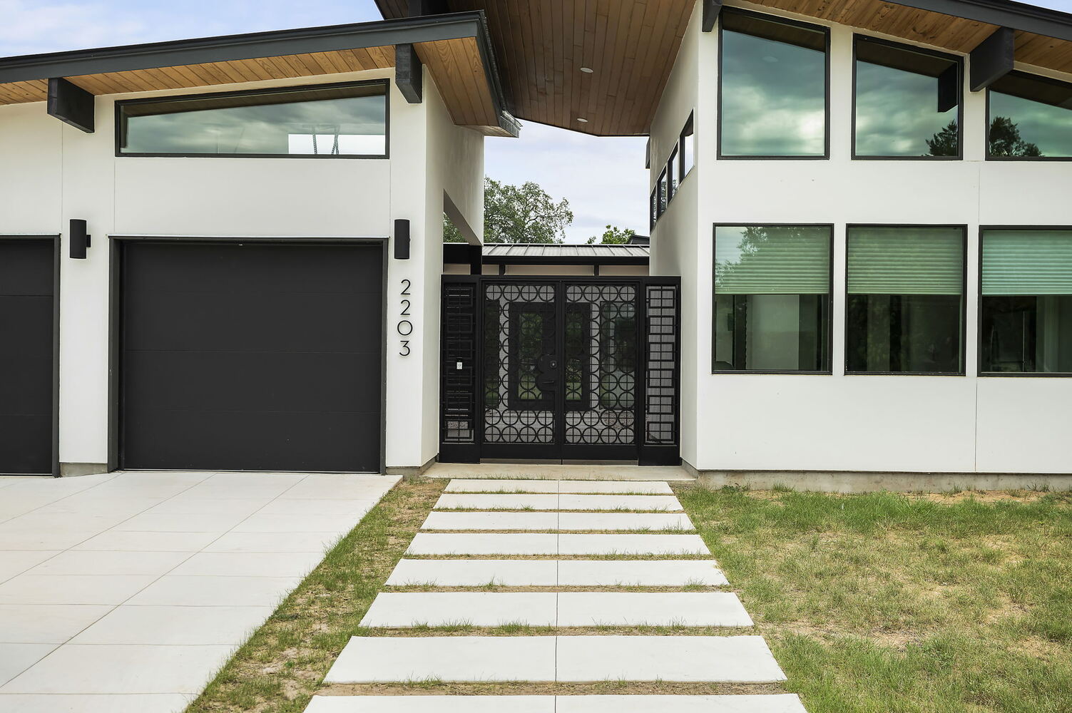 modern custom home entrance with concrete walkway and black metal gate by RedOven Builds in San Juan Dr Rio Grande TX