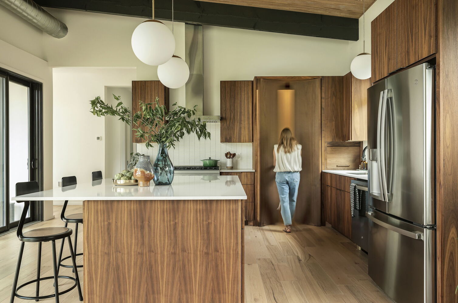 person entering hidden pantry in modern kitchen by RedOven Builds San Juan Dr Rio Grande TX