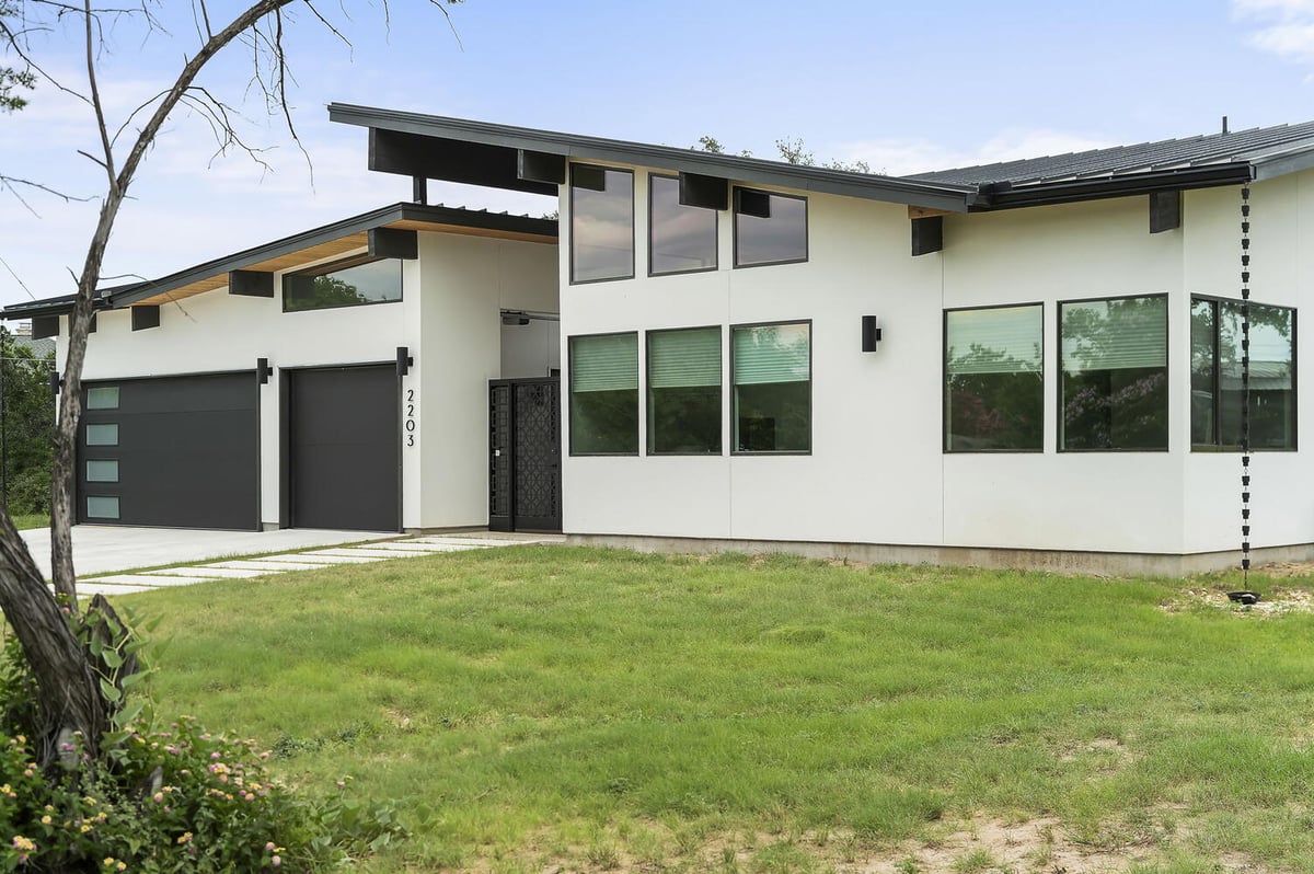 side angle of modern custom home with large windows and lawn by RedOven Builds in San Juan Dr Rio Grande TX