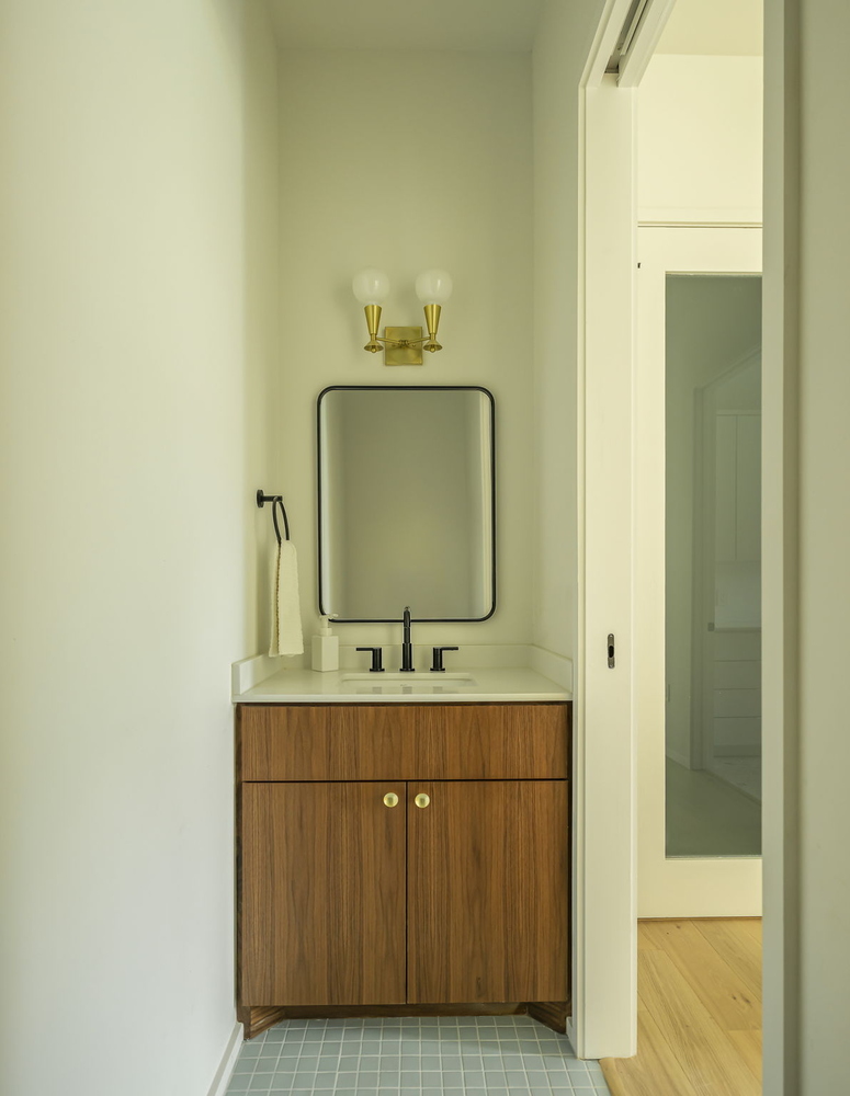 small bathroom vanity with wood cabinet and brass lighting in Rio Grande TX custom home by RedOven Builds