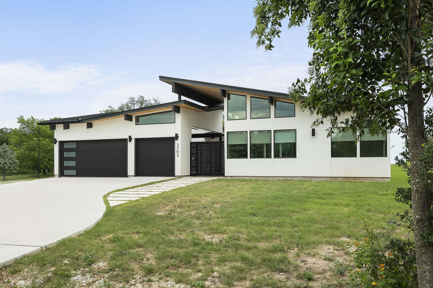 wide view of modern custom home exterior with large lawn by RedOven Builds in San Juan Dr Rio Grande TX