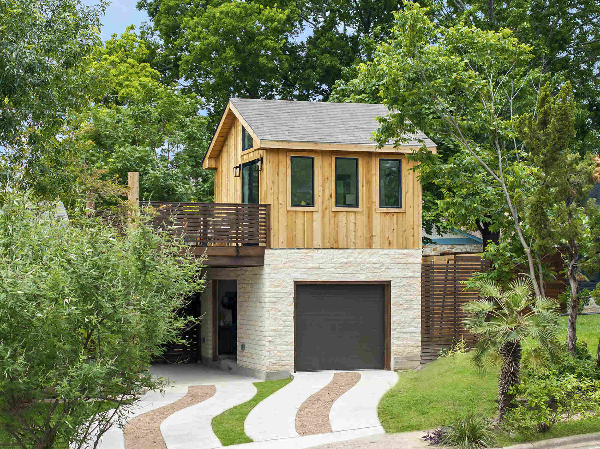 Exterior view of Austin home addition by RedOven Builds showcasing balcony deck and natural materials