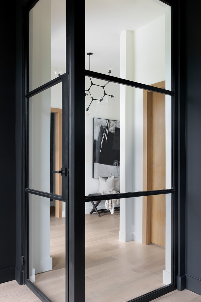 RedOven Builds glass interior door with black frame leading to modern hallway in Austin, TX