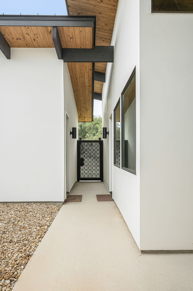 Exterior walkway with modern architecture and wood soffit in RedOven Builds custom home Rio Grande, TX
