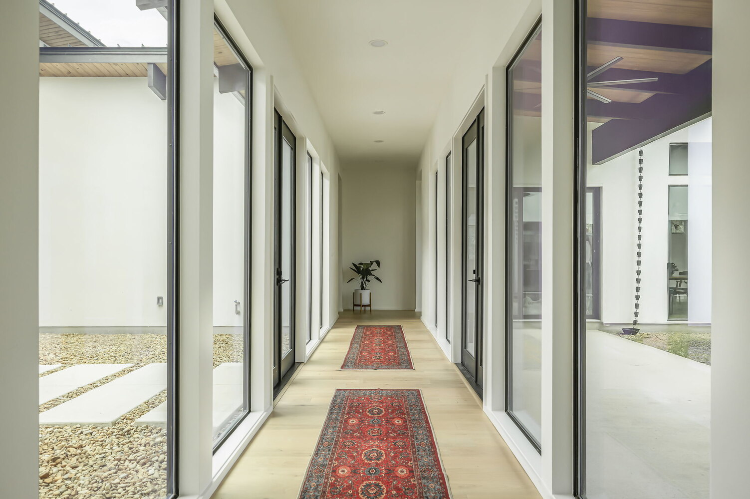RedOven Builds hallway with glass doors, wood flooring, and red runner rug in Rio Grande TX